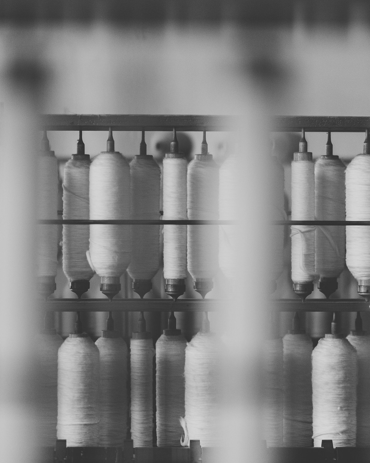 Rows of white thread spools seen through a softly blurred foreground